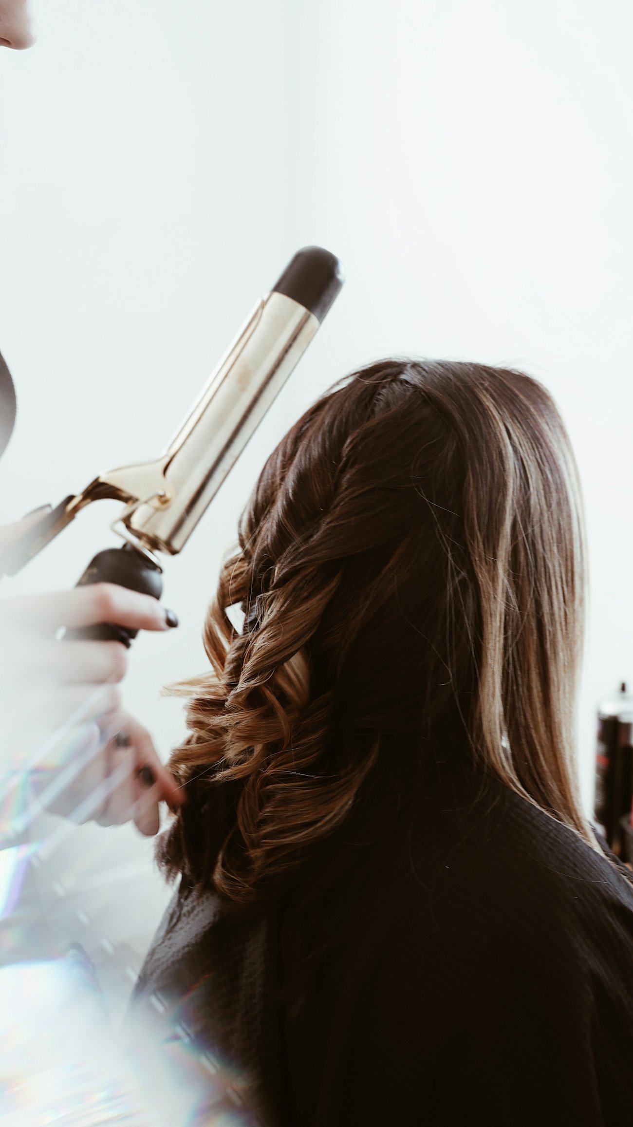 Peluquera dando forma a un rizo brillante con tenacillas