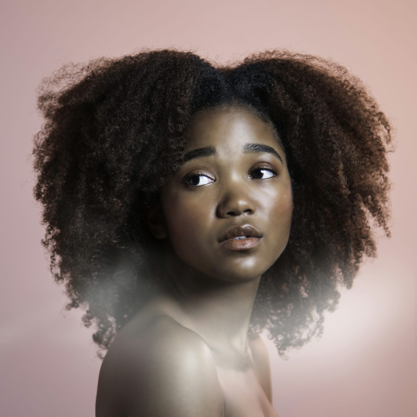 Mujer con el pelo rizado y voluminoso sobre un fondo rosado